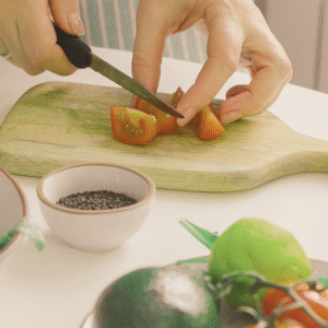 A photo of someone cutting a tomato to emphasize the importance of healthy eating for anxiety and stress management over the holidays.