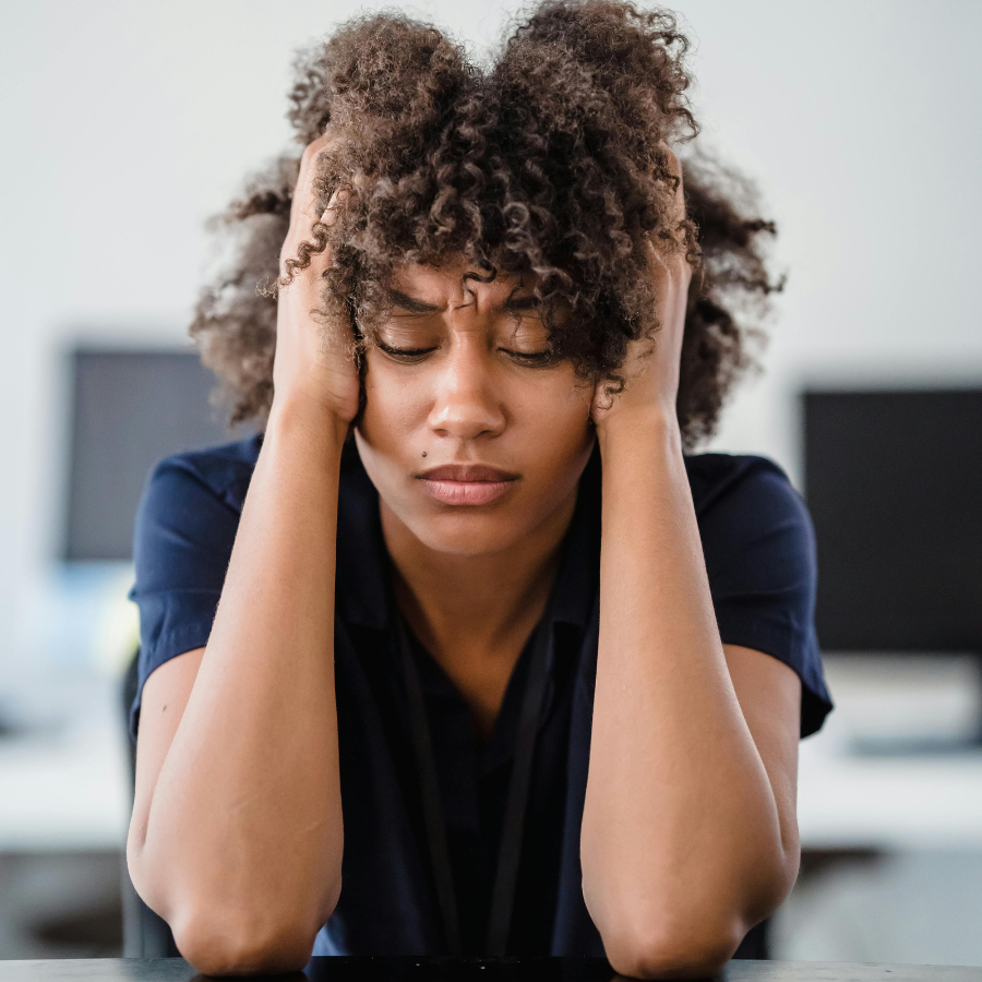 Person sitting with their head in their hands, feeling overwhelmed, symbolizing how manifesting culture can increase anxiety, with solutions from Orlando therapy.