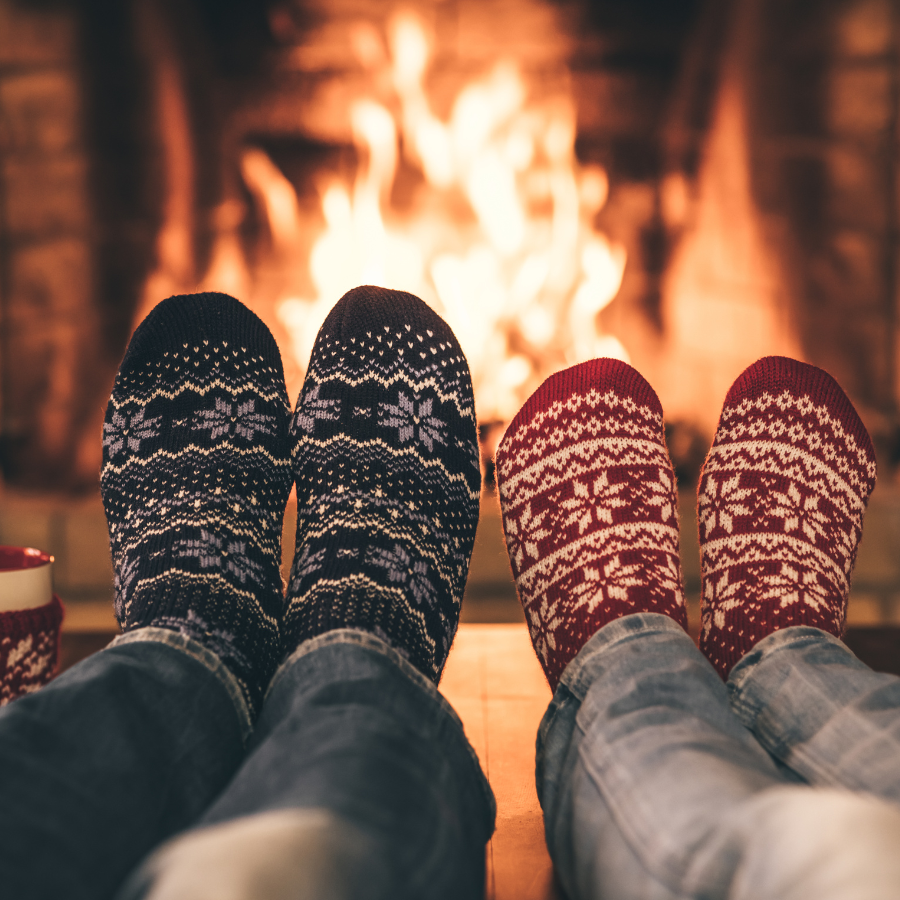 Two people in cozy socks relaxing by fireplace finding peace during holidays through Orlando anxiety therapy and healthy boundaries