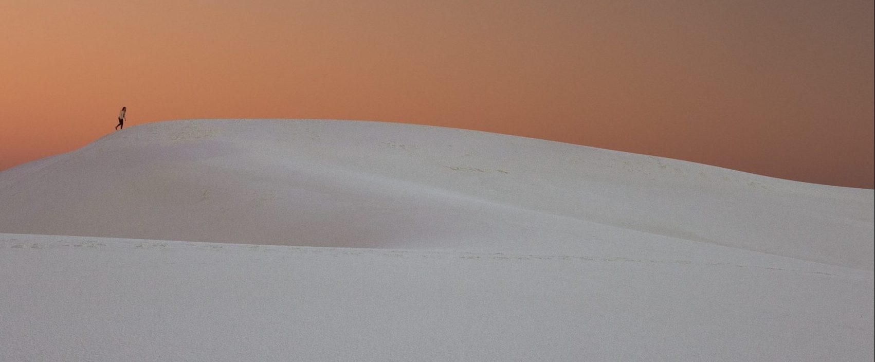 Individual walking alone in a serene desert landscape, promoting solitude and self-reflection.