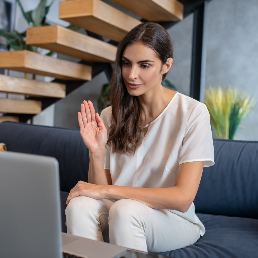 A woman engaging in online therapy session via laptop, waving at her therapist. Symbolizes the accessibility and convenience of virtual therapy for a stress-free holiday season