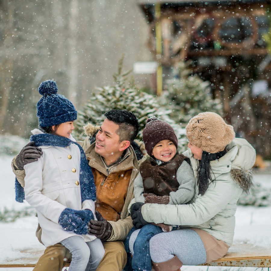 A young family wrapped in winter attire, smiling warmly as they enjoy the outdoors and start new holiday traditions. The photo captures their joy and togetherness during the festive season